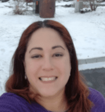 A woman with red hair and purple shirt smiling.